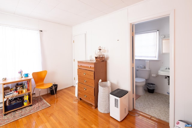 sitting room featuring ornamental molding and light wood-type flooring