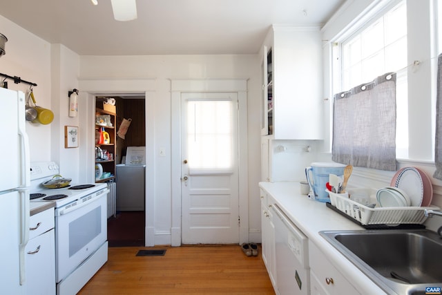 kitchen featuring washer / dryer, sink, light hardwood / wood-style flooring, white appliances, and white cabinets