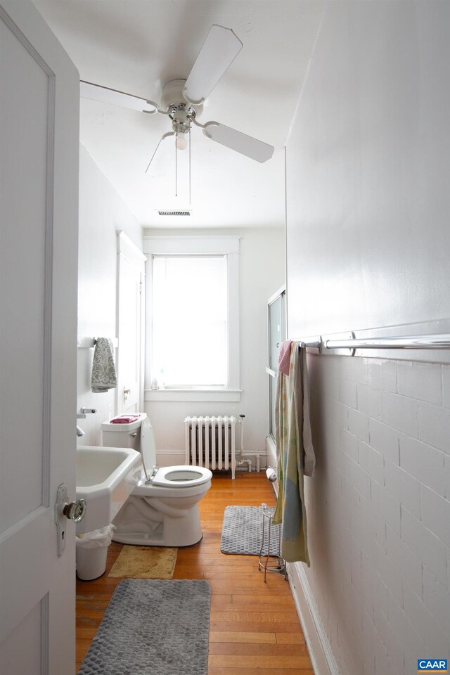 bathroom featuring hardwood / wood-style flooring, radiator, ceiling fan, and toilet