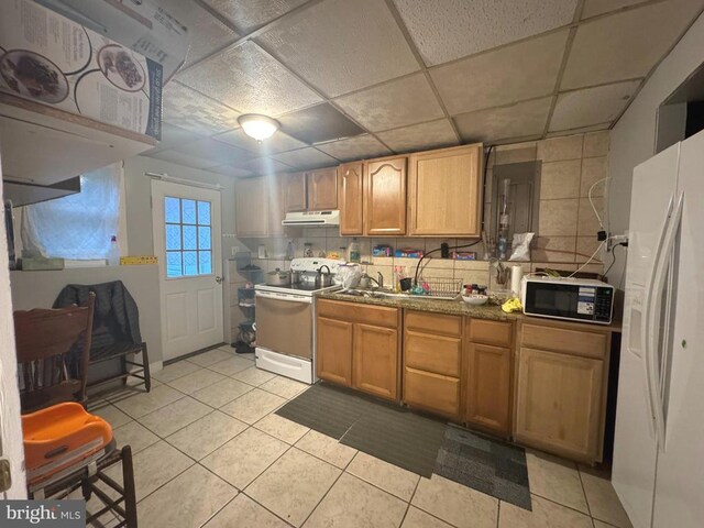 kitchen with light tile patterned floors, a drop ceiling, and white appliances