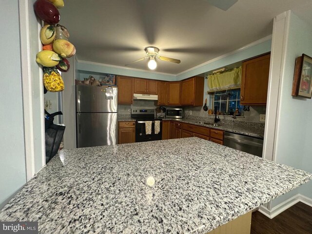 kitchen featuring light stone counters, sink, kitchen peninsula, and appliances with stainless steel finishes