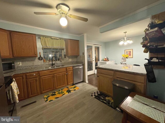 kitchen featuring sink, light hardwood / wood-style flooring, stainless steel appliances, decorative light fixtures, and french doors