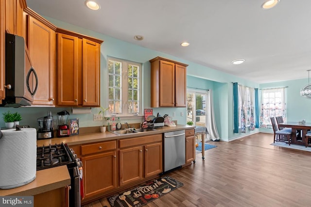 kitchen with recessed lighting, a sink, light countertops, appliances with stainless steel finishes, and brown cabinetry