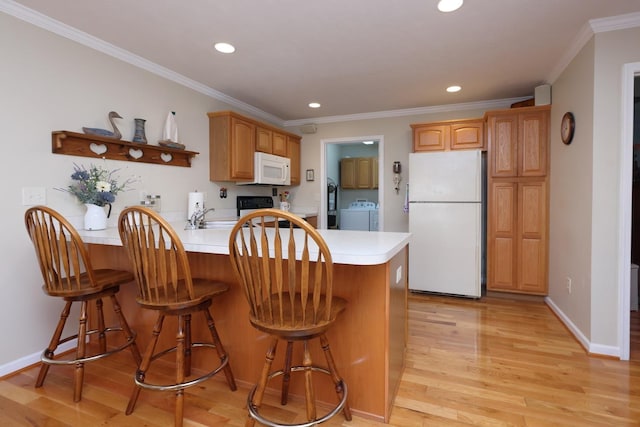 kitchen with washer / dryer, crown molding, light wood-type flooring, kitchen peninsula, and white appliances