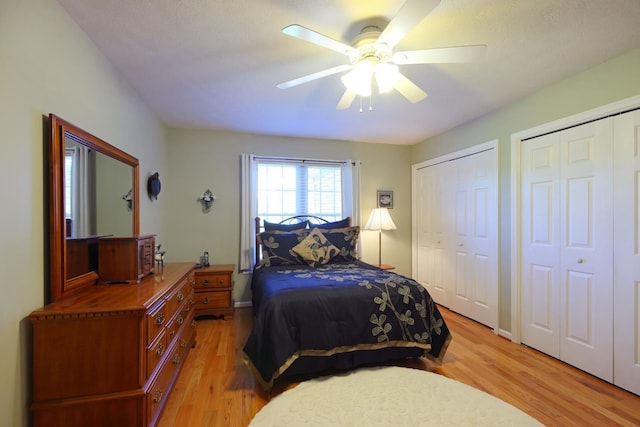 bedroom with ceiling fan, two closets, and light wood-type flooring