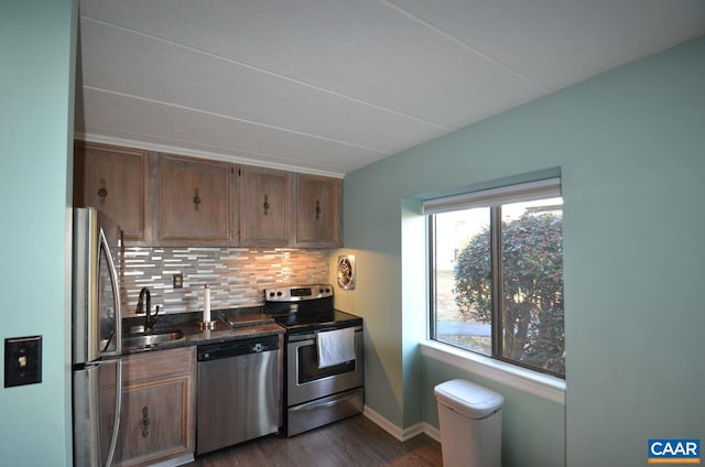 kitchen with appliances with stainless steel finishes, backsplash, a sink, and brown cabinets