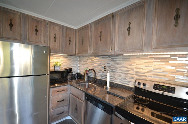 kitchen featuring stainless steel appliances, decorative backsplash, ornamental molding, a sink, and dark stone counters