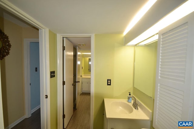 half bathroom featuring vanity, baseboards, and wood finished floors