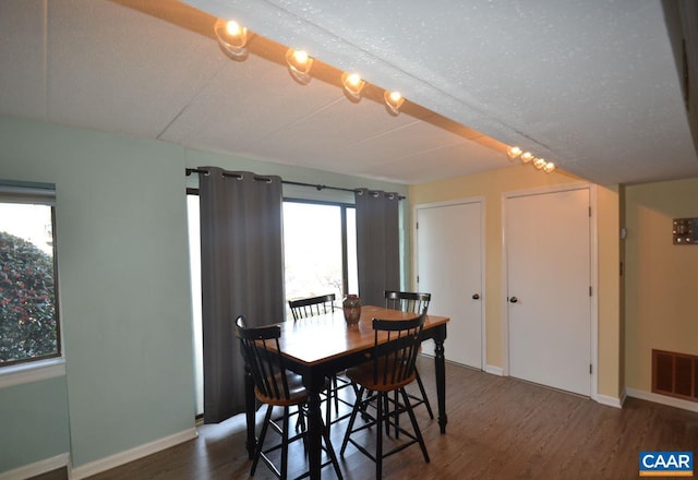 dining room featuring dark wood-type flooring, visible vents, and baseboards