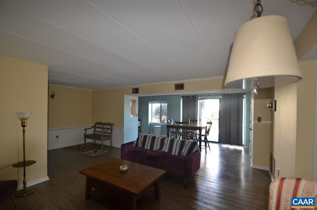 living area with baseboards, visible vents, dark wood-type flooring, and ornamental molding