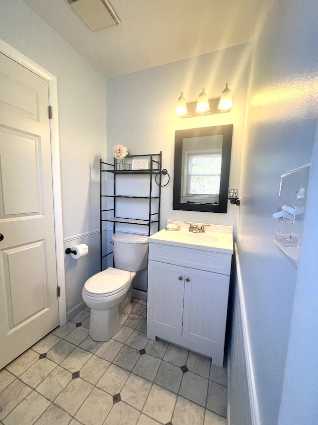 half bath featuring vanity and toilet