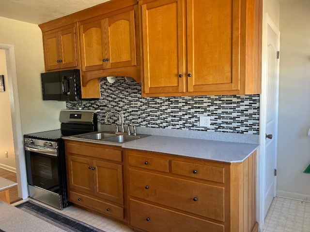 kitchen with electric stove, tasteful backsplash, brown cabinetry, a sink, and black microwave