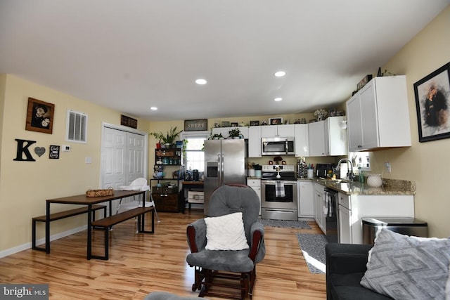 kitchen featuring white cabinetry, stainless steel appliances, sink, and light hardwood / wood-style flooring