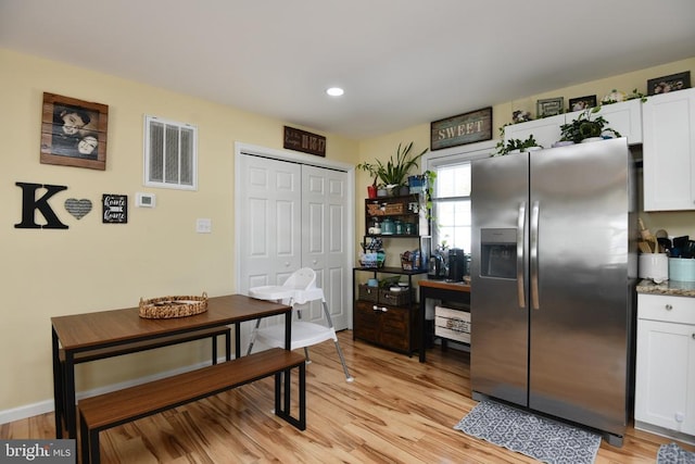 kitchen featuring stainless steel refrigerator with ice dispenser, white cabinetry, dark stone counters, and light hardwood / wood-style floors