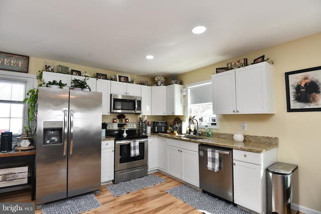 kitchen with stainless steel appliances, sink, and white cabinets