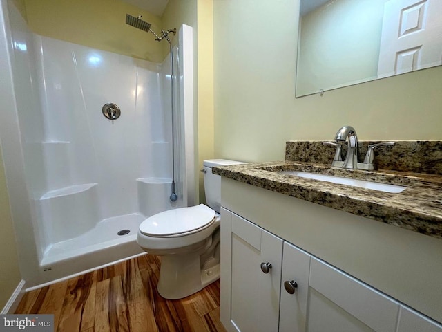 bathroom with vanity, toilet, hardwood / wood-style floors, and a shower