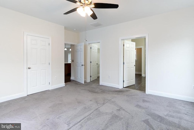 unfurnished bedroom with visible vents, connected bathroom, carpet flooring, baseboards, and ceiling fan