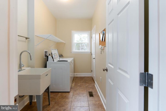 laundry area with a sink, light tile patterned floors, baseboards, laundry area, and washing machine and clothes dryer