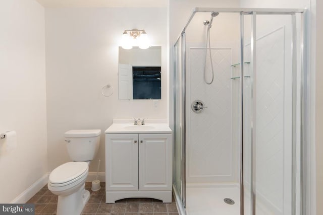 bathroom with toilet, a shower stall, tile patterned flooring, baseboards, and vanity