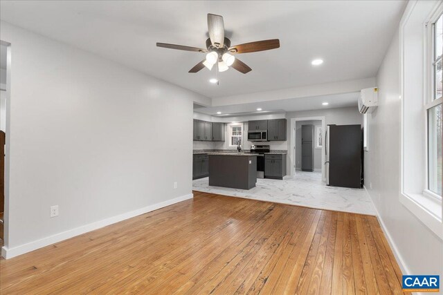 kitchen featuring light wood finished floors, stainless steel microwave, a sink, and a wealth of natural light