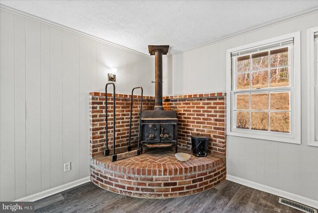 details featuring crown molding, a wood stove, hardwood / wood-style floors, and a textured ceiling