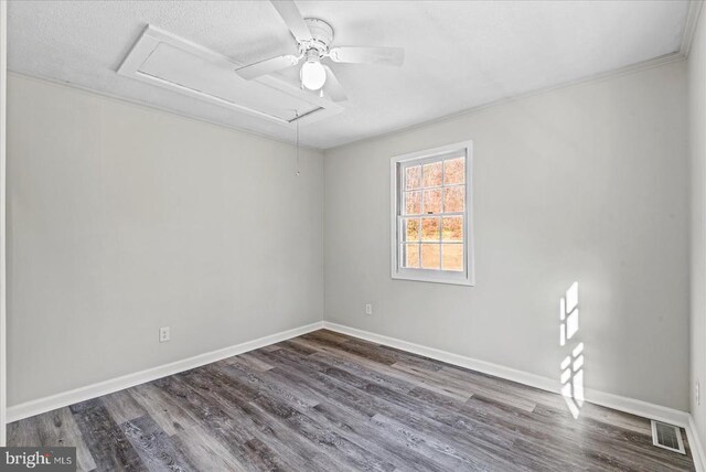 unfurnished room with ornamental molding, wood finished floors, attic access, and baseboards