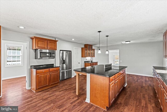 kitchen featuring a kitchen island, appliances with stainless steel finishes, dark wood-type flooring, and decorative light fixtures