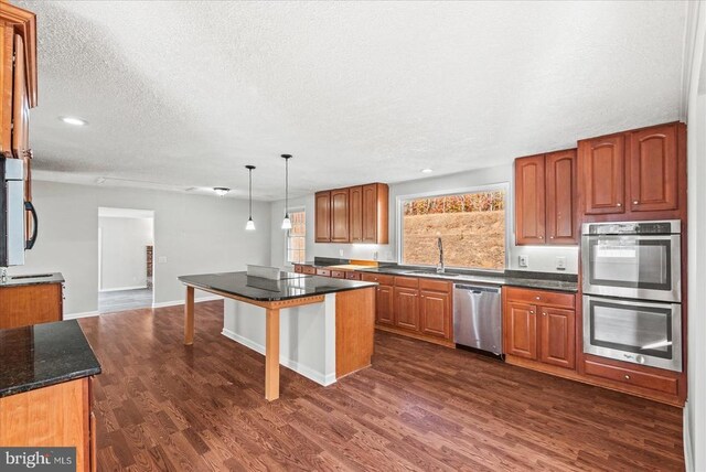 kitchen with sink, hanging light fixtures, stainless steel appliances, a center island, and dark hardwood / wood-style flooring