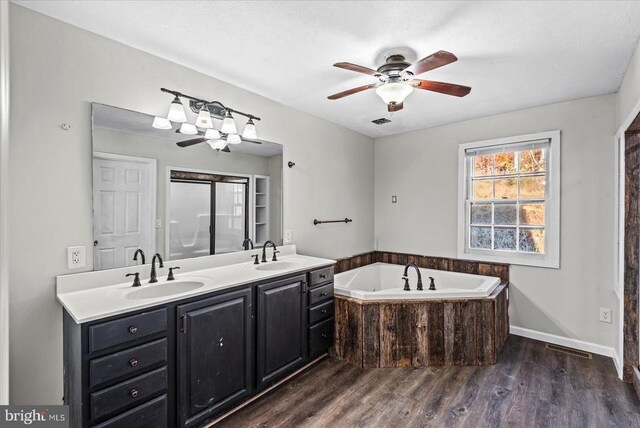 full bathroom featuring double vanity, wood finished floors, a sink, and a bath