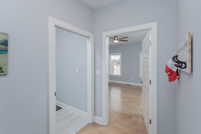 hallway featuring light wood-type flooring and baseboards