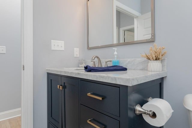 half bath with wood finished floors, vanity, and baseboards