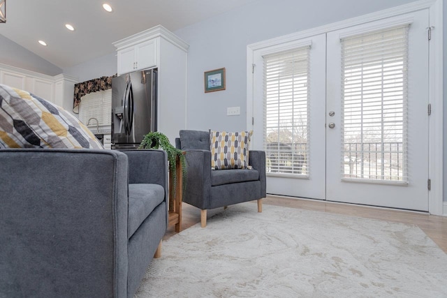 living area with vaulted ceiling, french doors, light wood-type flooring, and recessed lighting