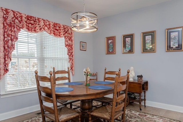 dining room with an inviting chandelier, baseboards, and wood finished floors