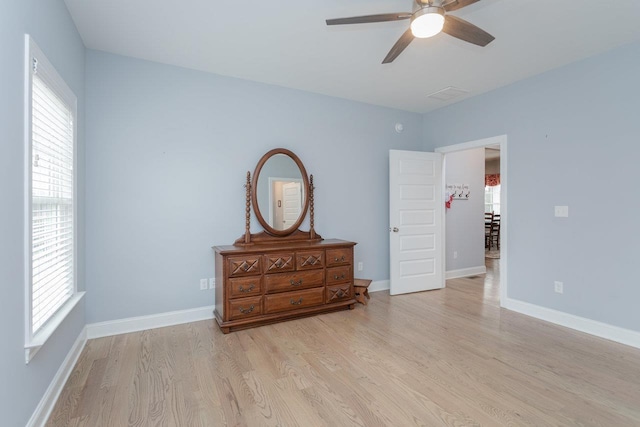 bedroom with baseboards, multiple windows, and light wood-style floors