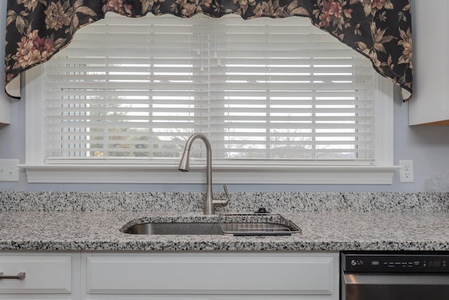 room details with dishwasher, light stone counters, white cabinets, and a sink