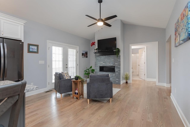 living room with ceiling fan, a fireplace, visible vents, baseboards, and light wood-style floors