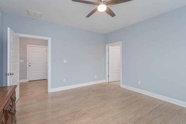 empty room featuring light wood-style floors, ceiling fan, visible vents, and baseboards