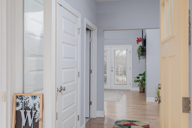 corridor with french doors, baseboards, and wood finished floors