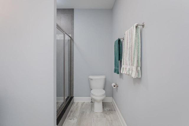 full bath with toilet, a stall shower, and baseboards