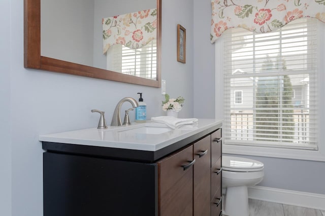 bathroom with toilet, baseboards, and vanity