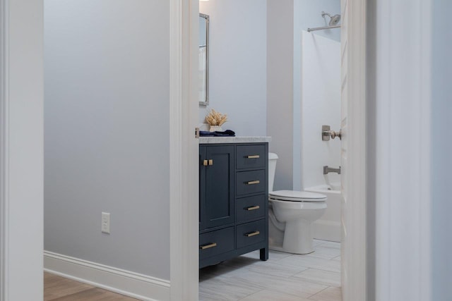 bathroom with baseboards, toilet, vanity, and shower / tub combination