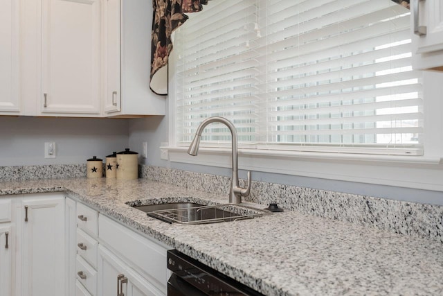 kitchen featuring dishwasher, a sink, white cabinets, and a healthy amount of sunlight