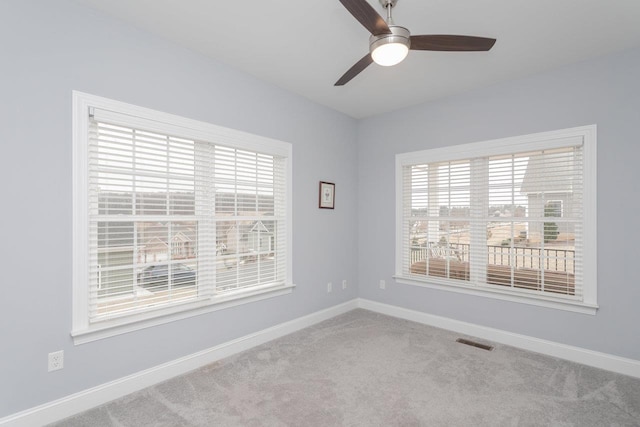 empty room with ceiling fan, carpet floors, visible vents, and baseboards