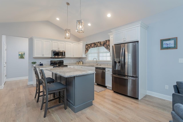 kitchen with light wood finished floors, white cabinets, a kitchen island, appliances with stainless steel finishes, and a sink