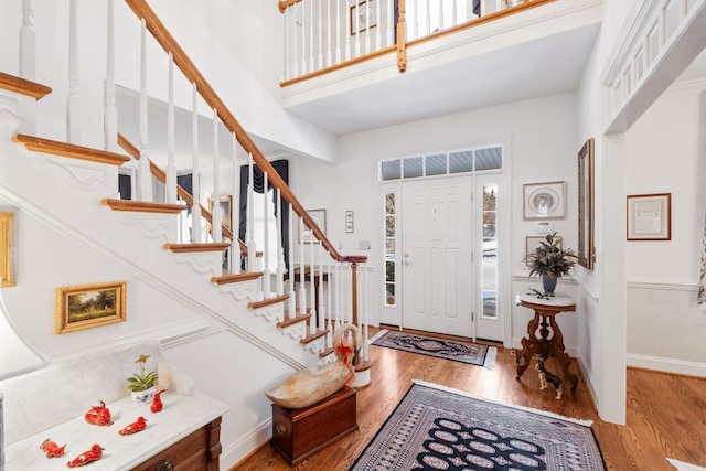 entryway with stairway, baseboards, a high ceiling, and wood finished floors