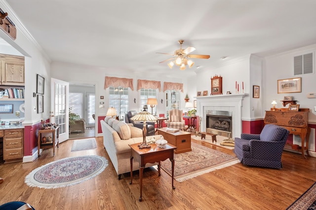 living room with visible vents, wood finished floors, ceiling fan, and a tile fireplace