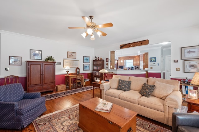 living room with crown molding, wood finished floors, and ceiling fan