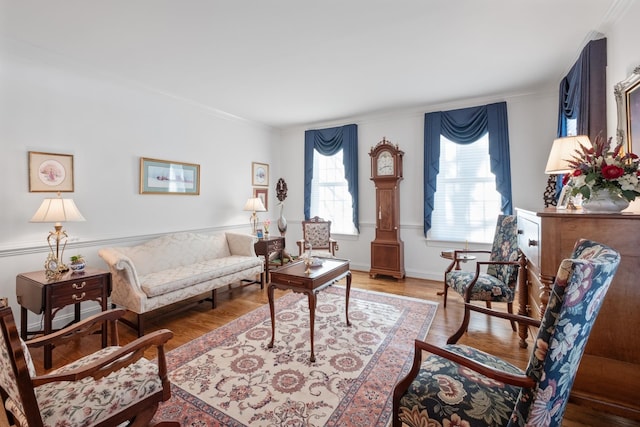 living area with crown molding, wood finished floors, and baseboards