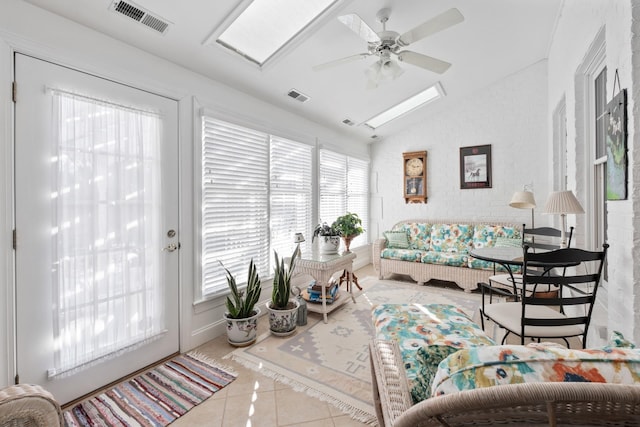 living area with lofted ceiling with skylight, visible vents, tile patterned flooring, and a ceiling fan