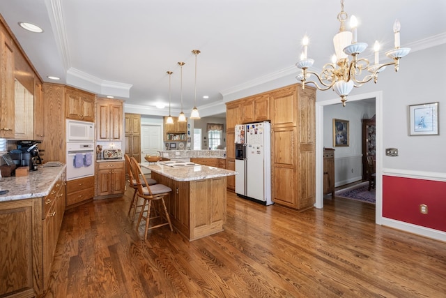 kitchen with a kitchen island, crown molding, a kitchen bar, white appliances, and dark wood-style flooring